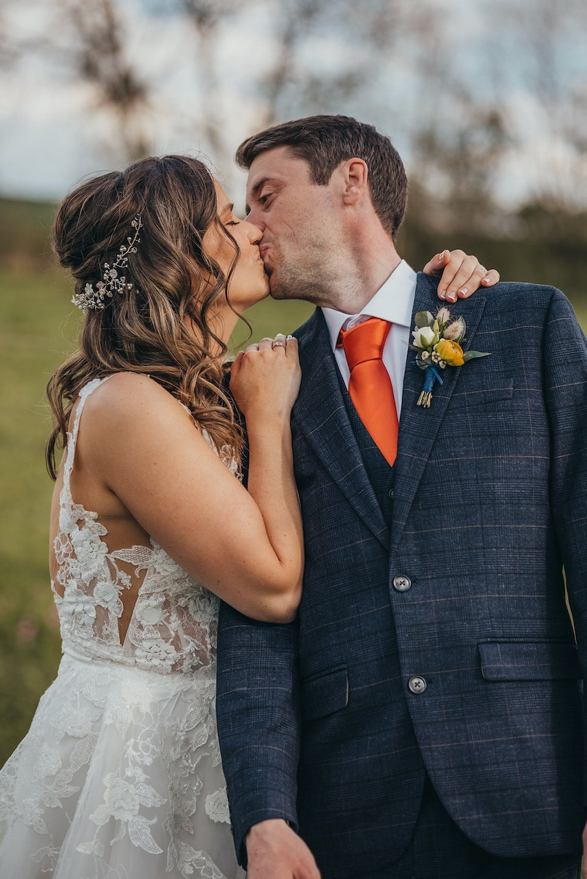 bride and groom showing bride in a detailed lace dress with a blush hair vine