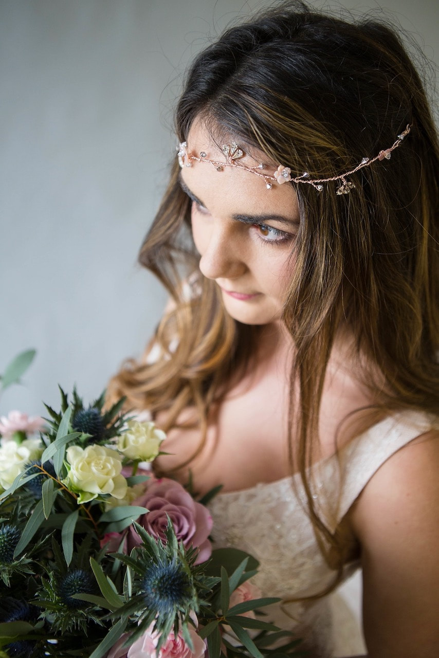 Bride wearing a blush and rose gold hairline with mother of pearl flowers and silver crystals