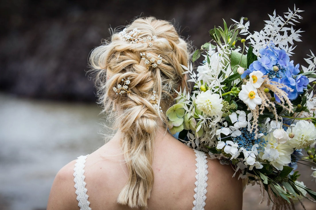 detailed textured bridal hair with gold and pale blue accessories and blue and cream and white dried flower wedding bouquet