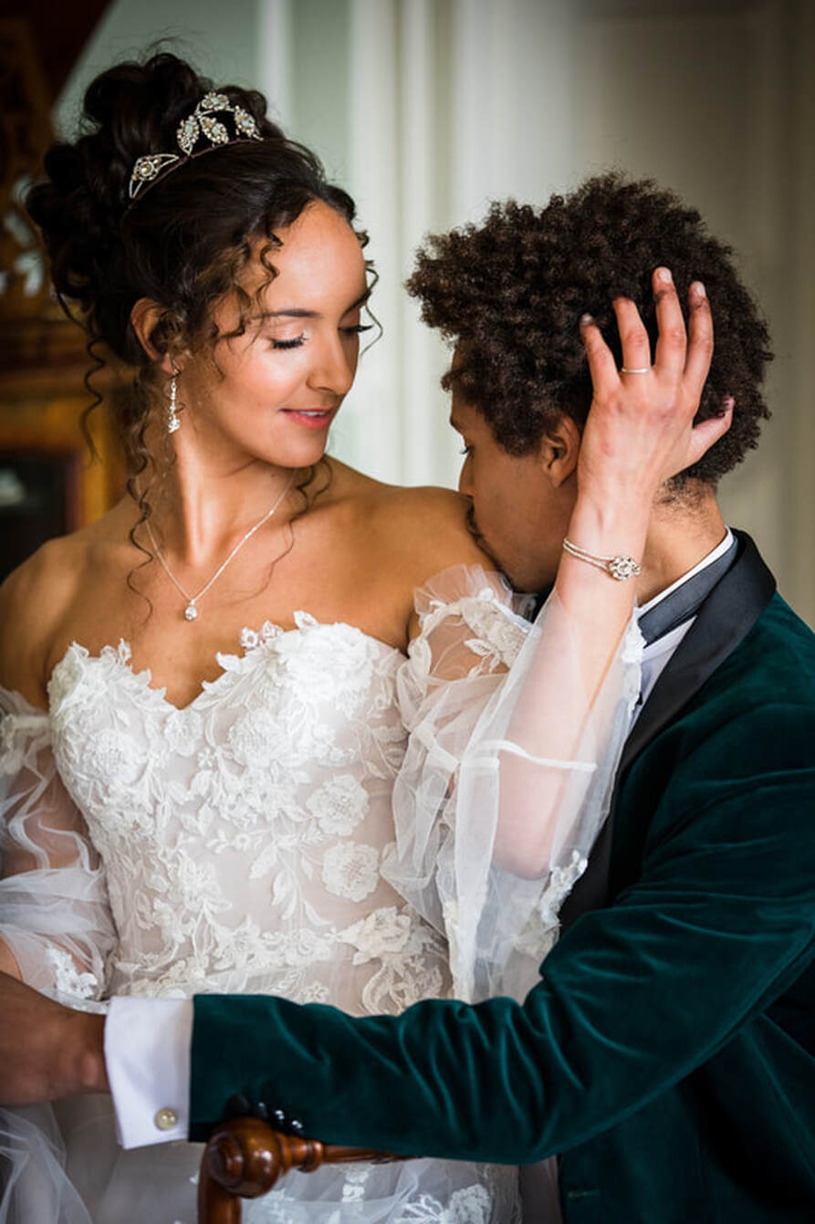 groom kissing brides shoulder in an embrace, diamanté's tiara, necklace and earrings bride with curly dark hair