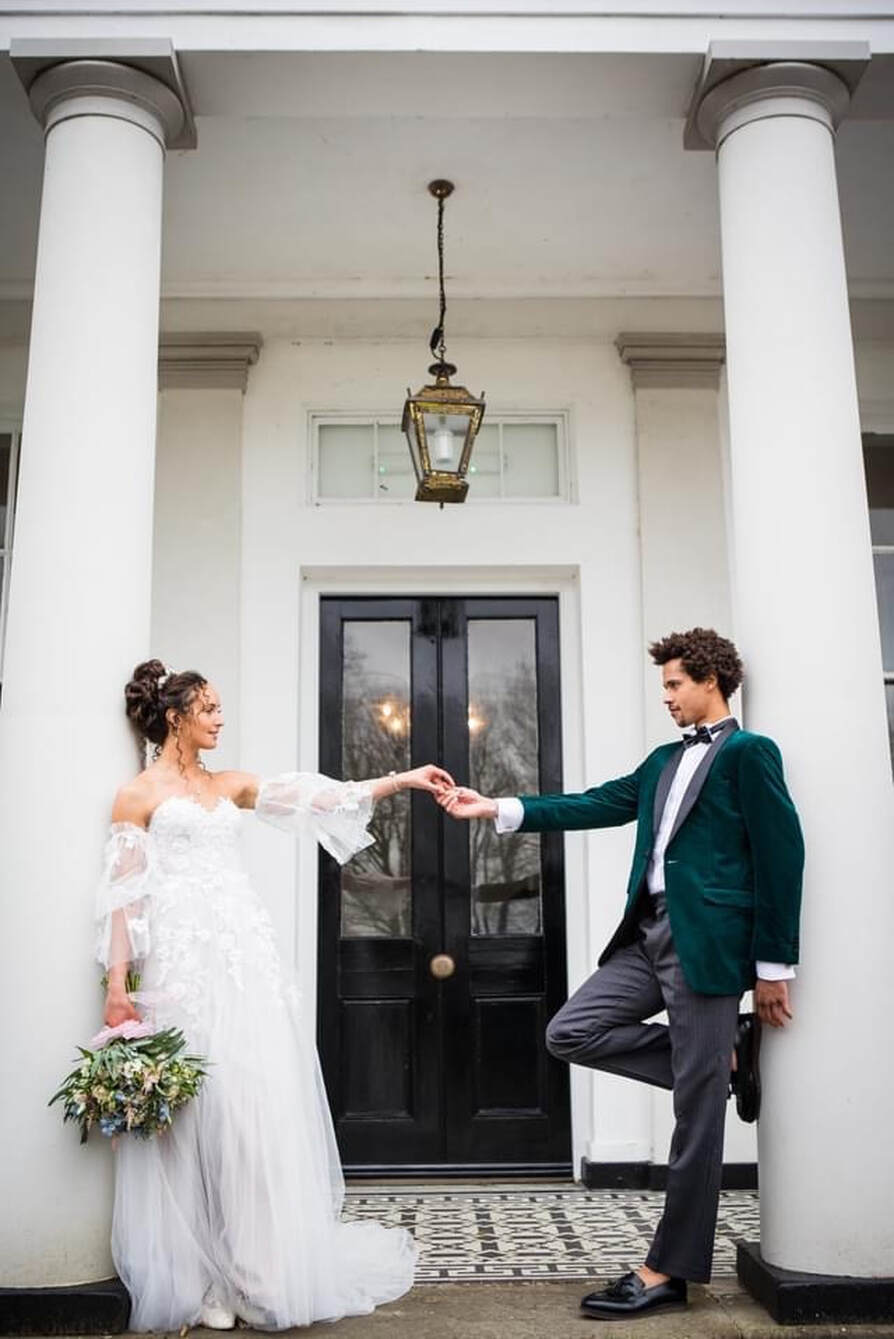 Bride and groom outside the country house with bouquet and groom with dark green velvet jacket