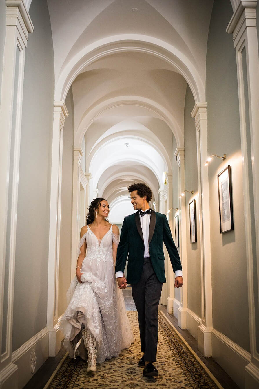 bride and groom holding hands walking along the Manor House regency hallway smiling after getting married
