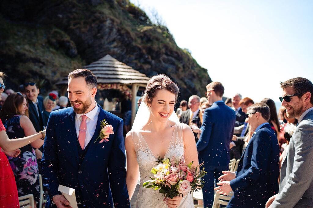 bride and groom confetti moment at Tunnels Beach in Ilfracombe lots of smiling wedding guests