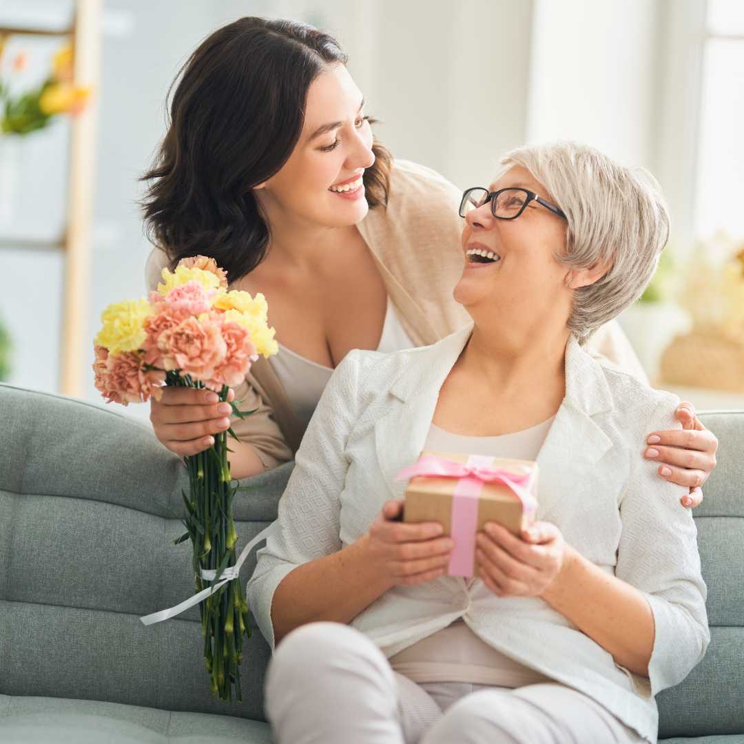 Daughter giving Mum a jewellery gift and flowers for Mother's Day