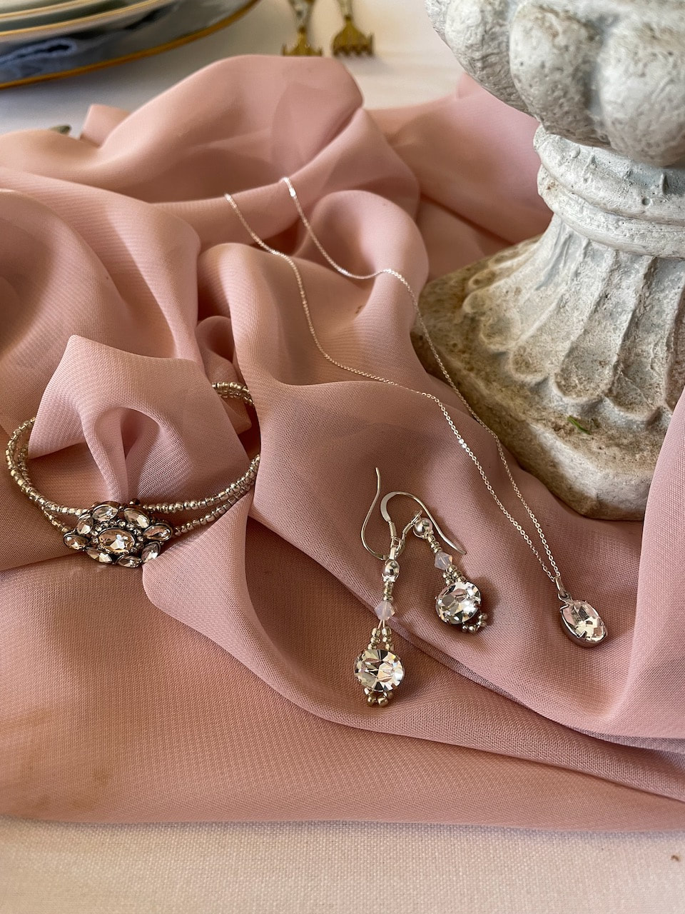 Sparkly earrings, necklace and bracelet for a wedding day on dusky pink blush  material